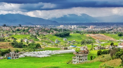 Fototapeta na wymiar Green Farm Land field and Kathmandu city in the backdrop on a cloudy day
