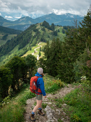  Woman with backpack hiking in forested mountains enjoying the scenic view - 328254426