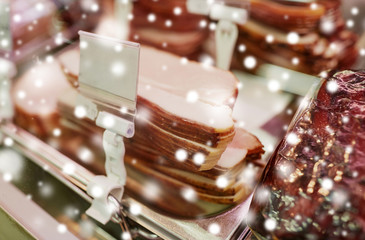 meat, sale and food concept - ham at grocery store stall over snow