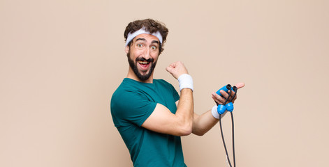 young cool sports man with a jump rope against flat wall