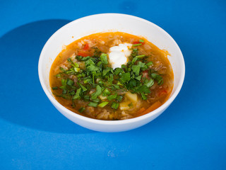 Soup in a white plate. Red soup of Russian cabbage, tomato paste and herbs. Side view