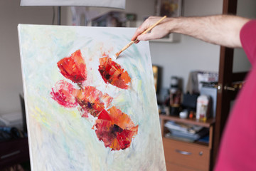 Artist's hand with a brush paints on a white canvas. The beginning of a picturesque picture