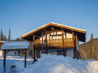 Fototapeta na wymiar Wooden two-story Alpine-style house. Hotel in the ski resort Gornaya Salanga. Winter day