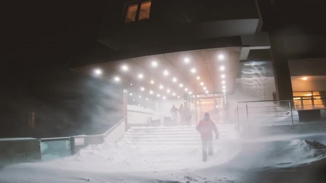 Blizzard and very strong snow windstorm in a mountain resort. People are running for safety.