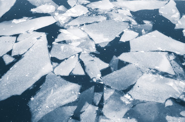 Fototapeta na wymiar Fragments of melting ice float on a river water