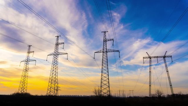 Time Lapse of Electricity Pylons and High Voltage Power Line at Dusk. Transmission Towers in a Row on the background of Beautiful Cloudy Sky in Europe, Germany