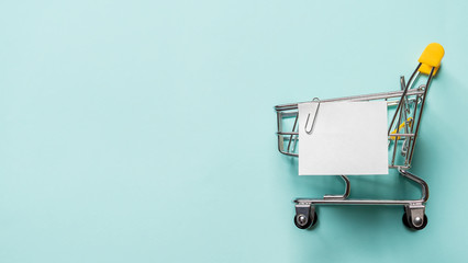 Shopping cart and white paper note list over blue background. Shopping concept on blue background....