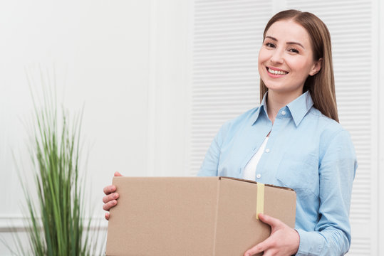 Smiling woman holding a package indoors