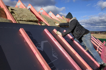 Insulation and waterproofing of the roof surface, the worker nails the film to the boards.