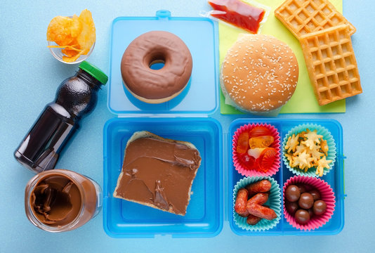 Lunch box with unhealthy food on blue background, top view