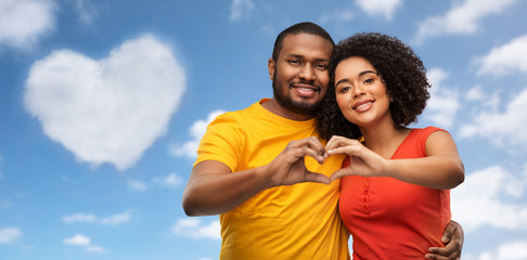 love, valentines day and people concept - happy african american couple making hand heart gesture...