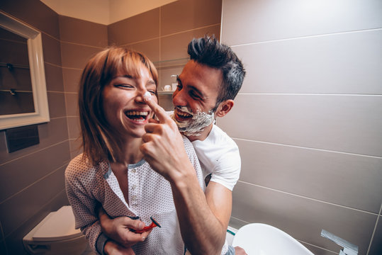 Beautiful young couple of lovers in the bathroom having fun playing with shaving foam. - Powered by Adobe