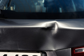 A dent in the body of a silver car