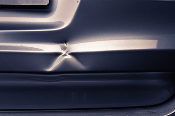 A dent in a metal fold of a silver car in exciting light.