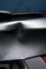 A dent in a metal fold of a silver car in exciting light.