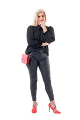 Thinking and wondering middle aged stylish lady with hand on chin looking at camera. Full body length isolated on white background.