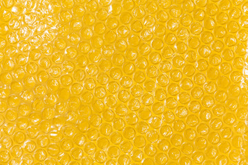 Bubble wrap top view on yellow background.
