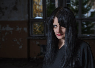 Fototapeta na wymiar portrait of gothic brunette woman standing head down in large empty hall
