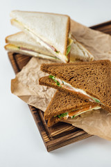 Dark and white bread sandwiches on a wooden board, isolated on white background
