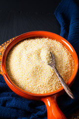 Food concept organic raw couscous in orange bowl on blask slate stone board with copy space © TYSB