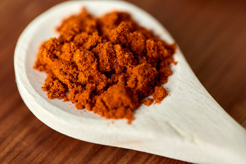 food, culinary and unhealthy eating concept - close up of turmeric on wooden spoon