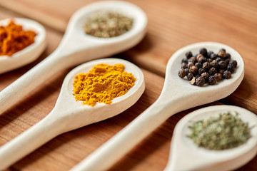 food, culinary and unhealthy eating concept - spoons with different spices on wooden table