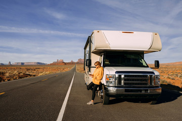 A woman travels by motorhome through Monument Valley in the USA desert and checks her mobile phone...