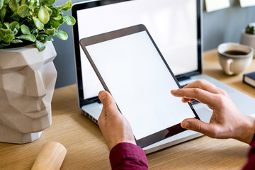 Close up of stylish composition with  businessman, mock up tablet screen, cup of coffee, plants and office supplies in modern concept.