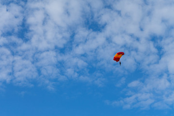 Parachuter descending with parachute against blue sky. Skydiver in the sky. People under parachute in the sky.