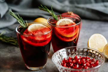 Pomegranate drink in a glass with lemon and rosemary