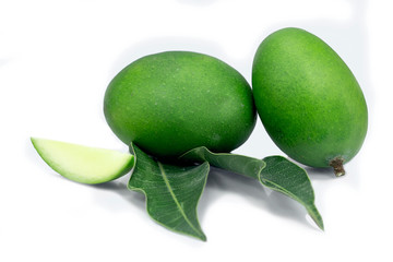 raw green mango with mango leaves and slice of mango