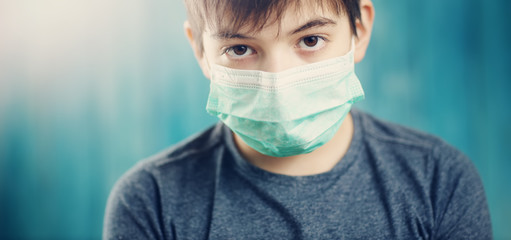 boy in medical face protection mask indoors on blue background