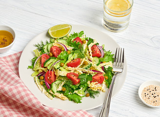 Fresh salad with cherry tomatoes, savoy cabbage, cucumeber on dish. Healthy summer salad vegetarian meal concept. Tasty mixed leaves, tomatoes and mix vegetable salad on white wood