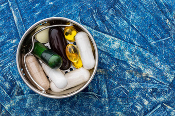 Biologically active additives in a small iron container, on a blue wooden surface.