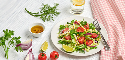 Fresh salad with cherry tomatoes, savoy cabbage, cucumeber on dish. Healthy summer salad vegetarian meal concept. Tasty mixed leaves, tomatoes and mix vegetable salad on white wood