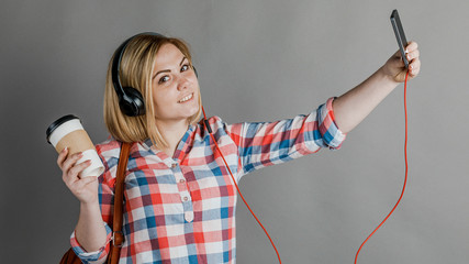 A beautiful girl makes a self-portrait using her phone on a gray background