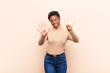 young pretty black womansmiling and looking friendly, showing number nine or ninth with hand...