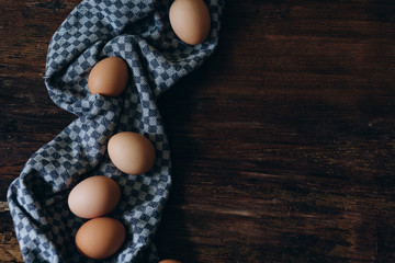 brown chicken eggs on a vintage background. On the side lies a blue linen cloth
