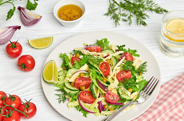 Fresh salad with cherry tomatoes, savoy cabbage, cucumeber on dish. Healthy summer salad vegetarian meal concept. Tasty mixed leaves, tomatoes and mix vegetable salad on white wood