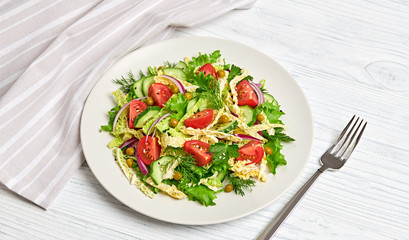 Fresh salad with cherry tomatoes, savoy cabbage, cucumeber on dish. Healthy summer salad vegetarian meal concept. Tasty mixed leaves, tomatoes and mix vegetable salad on white wood