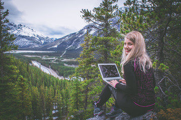 Digital nomad woman working on her laptop in the mountains