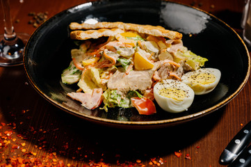 Caesar salad on black plate on wooden table