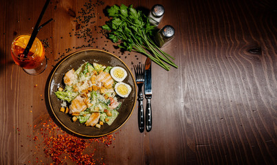 Caesar salad on black plate on wooden table.Top view