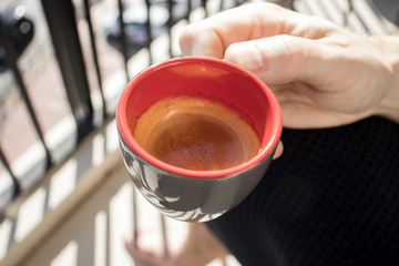 photograph of the hands of a man holding a coffee cup. Espresso cup with the sea on the background. Close up