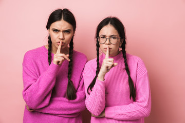 Image of two young girls keeping fingers at lips and asking to be quiet