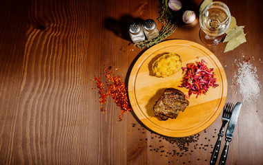 A juicy piece of fried meat lies on a cutting board against a wooden table.Top view