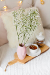 Spring home cozy interior. A bouquet of flowers in a vase, a cup of tea, decor on the sofa.