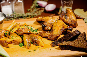 Barbecue grilled chicken wings close up with fries, sauce on wooden background. Meat food concept.