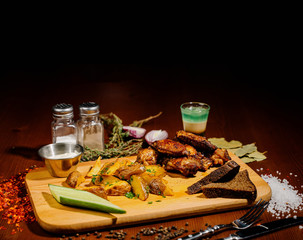 Barbecue grilled chicken wings close up with fries, sauce on wooden background. Meat food concept.