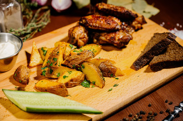 Barbecue grilled chicken wings close up with fries, sauce on wooden background. Meat food concept.